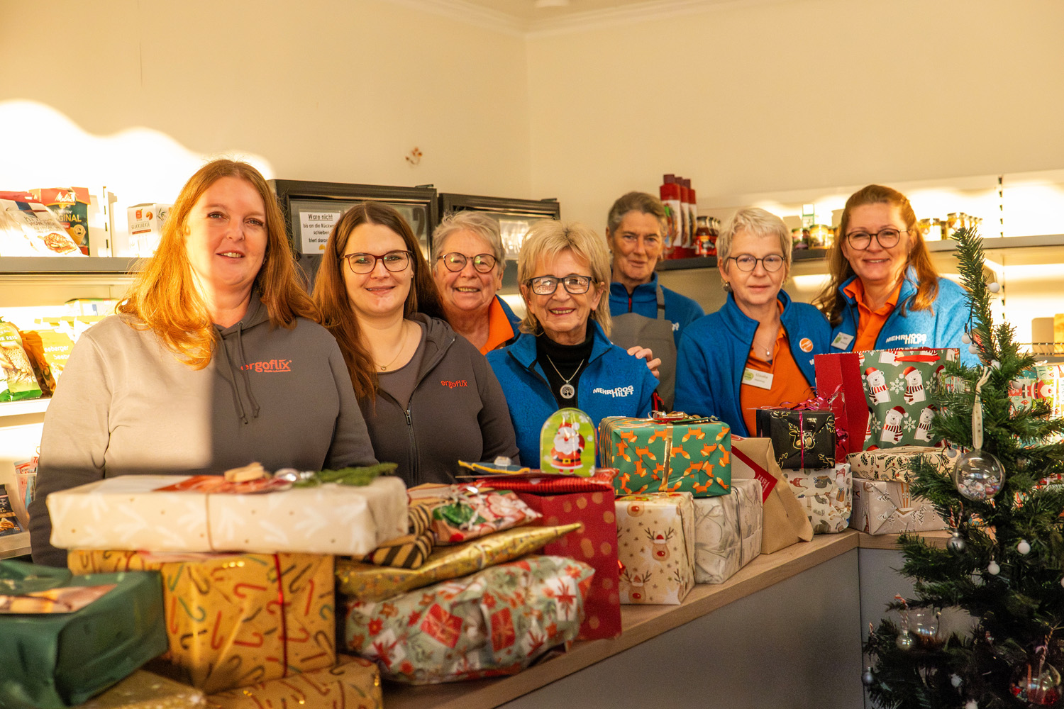 Das Bild zeigt 7 Frauen mittleren bis h&ouml;heren Alters, die hinter einer Theke stehen, auf der Theke stehen ganz viele eingepackte Geschenke.